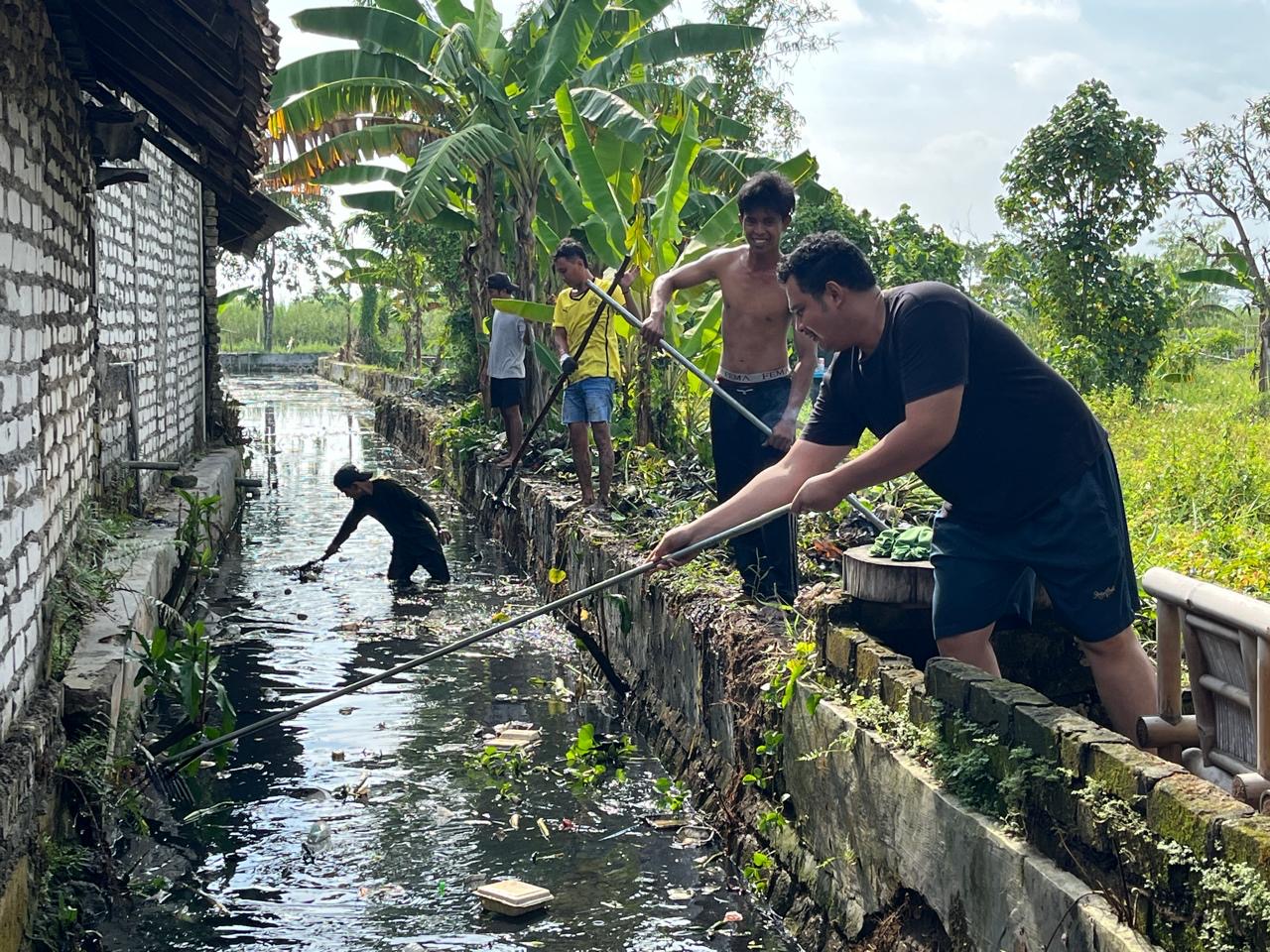 Reza Teguh Wibowo bersama warga saat melakukan kerja bakti pembersihan di sepanjang Kali Kepang, Kampung Tarogan, Kelurahan Kemayoran, Kecamatan Bangkalan, Minggu (21/12/2025).