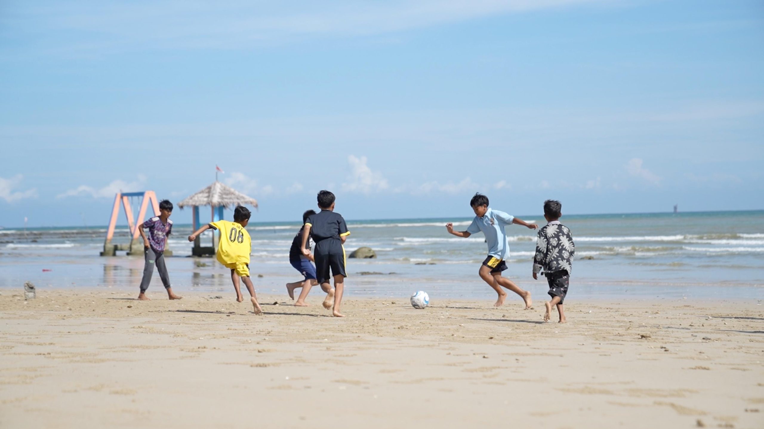 Anak-anak bermain sepak bola di Pantai Pasir Putih Tlangoh, Bangkalan, Jawa Timur. Pemulihan pesisir melalui pemasangan terumbu buatan hexa reef tak hanya menahan abrasi, tetapi juga menghidupkan kembali ruang publik dan aktivitas sosial warga di kawasan pantai.