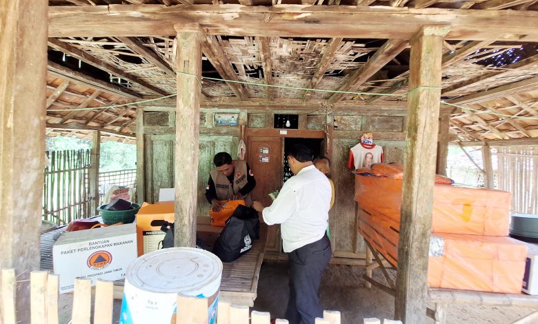 Petugas BPBD Kabupaten Sampang menyalurkan bantuan logistik kepada dua lansia yang tinggal di gubuk tak layak huni di Dusun Lenteng, Desa Nyeloh, Kecamatan Kedungdung, Selasa (13/1/2026). Bantuan diberikan sebagai bentuk kepedulian kemanusiaan untuk menopang kebutuhan dasar dan kondisi kesehatan lansia rentan.