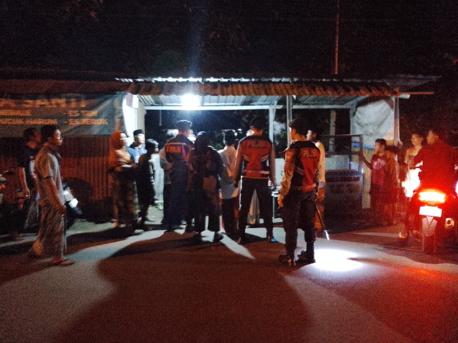 Petugas kepolisian bersama warga berada di lokasi kejadian di Kelurahan Mlajah, Bangkalan.  tempat seorang wanita ditemukan pingsan di pinggir jalan usai diduga menjadi korban penganiayaan oleh suami sirinya.