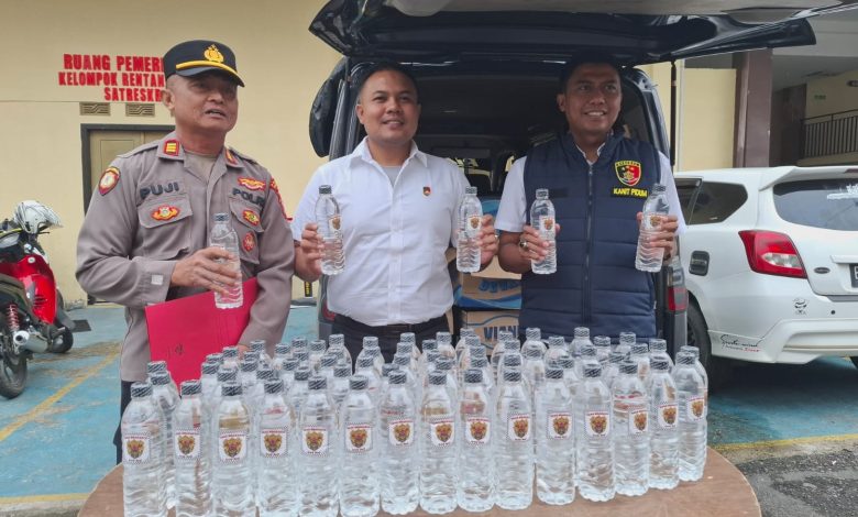 Petugas Satreskrim Polres Sampang menunjukkan barang bukti minuman keras jenis Arak Bali yang berhasil diamankan dari sebuah mobil travel di kawasan Terminal Trunojoyo, Sampang.