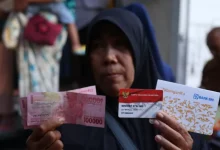 Seorang warga menunjukkan uang tunai dan Kartu Keluarga Sejahtera (KKS) usai menerima bantuan sosial Program Keluarga Harapan (PKH). Pemerintah melakukan graduasi dan pencoretan penerima yang dinilai telah mandiri | Foto Ilustrasi