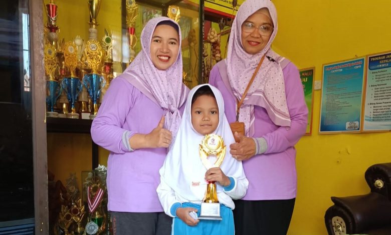 Keterangan Foto: Foto: Nadia Hairul Putri Hidayati, siswi SDN Kraton 2 Bangkalan, saat memegang piala bersama Kepala Sekolah Erma Agustiningsih (kanan).