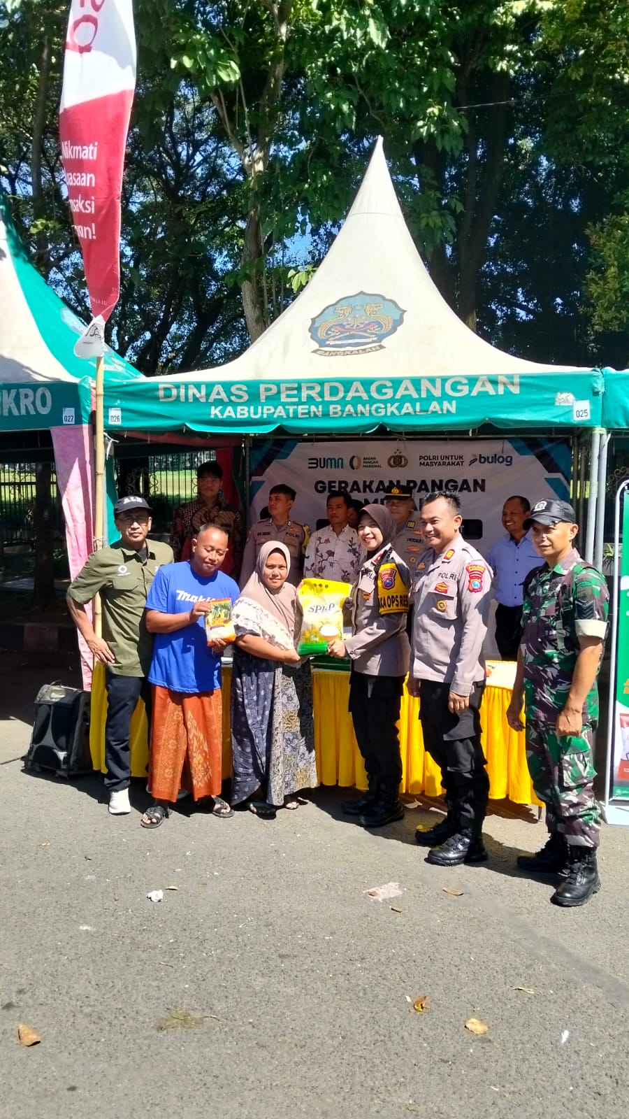 Petugas Polres Bangkalan bersama Perum Bulog Kantor Cabang Madura menyerahkan secara simbolis bahan pokok kepada warga dalam kegiatan Gerakan Pangan Murah (GPM) di stan Dinas Perdagangan Kabupaten Bangkalan, Jumat (13/3/2026). Program ini digelar untuk menjaga stabilitas harga pangan dan membantu masyarakat menjelang Hari Raya Idul Fitri.