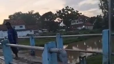 Seorang warga berdiri di atas jembatan di kawasan Sungai Tunjung, Bangkalan, memantau lokasi pencarian bocah 8 tahun yang diduga tenggelam bersama ibunya.