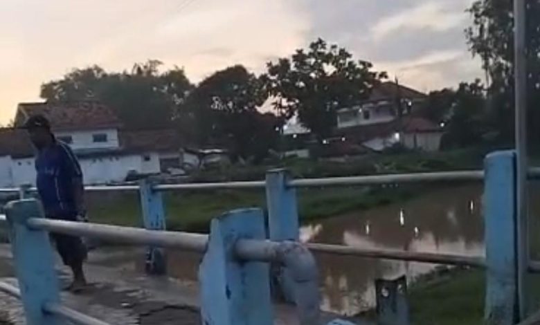 Seorang warga berdiri di atas jembatan di kawasan Sungai Tunjung, Bangkalan, memantau lokasi pencarian bocah 8 tahun yang diduga tenggelam bersama ibunya.