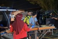Petugas dan warga mengevakuasi korban kecelakaan dari mobil pikap ke ambulans di Jalan Halim Perdana Kusuma, Bancaran, Bangkalan, Minggu malam (5/4/2026). Insiden tabrak belakang tersebut menewaskan satu orang dan menyebabkan empat lainnya luka-luka.