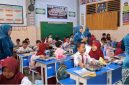 Guru SDN Demangan 1 Bangkalan mengenakan kebaya saat mengajar dan membagikan makanan kepada siswa dalam rangka memperingati Hari Kartini, mengenang perjuangan Raden Ajeng Kartini di dunia pendidikan.