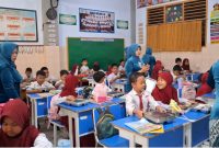 Guru SDN Demangan 1 Bangkalan mengenakan kebaya saat mengajar dan membagikan makanan kepada siswa dalam rangka memperingati Hari Kartini, mengenang perjuangan Raden Ajeng Kartini di dunia pendidikan.