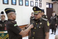 Kajari Sampang Mochamad Iqbal menyematkan tanda jabatan kepada Tunjung Sughandiko saat prosesi pelantikan dan serah terima jabatan Kasi Pidum di Kejaksaan Negeri Sampang, Jumat (24/4/2026).
