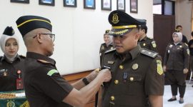 Kajari Sampang Mochamad Iqbal menyematkan tanda jabatan kepada Tunjung Sughandiko saat prosesi pelantikan dan serah terima jabatan Kasi Pidum di Kejaksaan Negeri Sampang, Jumat (24/4/2026).