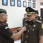 Kajari Sampang Mochamad Iqbal menyematkan tanda jabatan kepada Tunjung Sughandiko saat prosesi pelantikan dan serah terima jabatan Kasi Pidum di Kejaksaan Negeri Sampang, Jumat (24/4/2026).